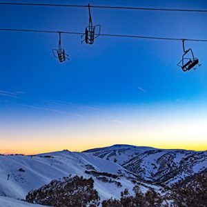 Mt Hotham chairlift at sunset with snow covered slopes in the background