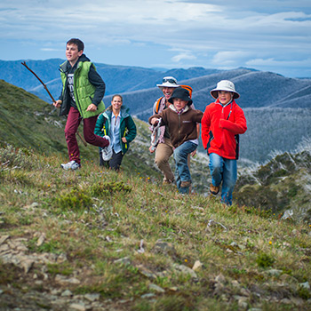 Children and their parents running up a hill on Mt Hotham in the Autumn