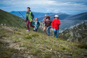 Children and their parents running up a hill on Mt Hotham in the Autumn